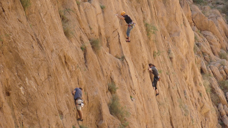Three climbers scaling a rock face.