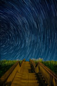 Photo d'un pont en bois sur un ciel de nuit étoilé.